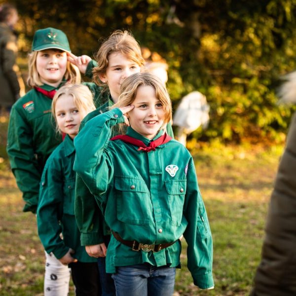 To spejderledere viser en færdselstavle for en gruppe børn